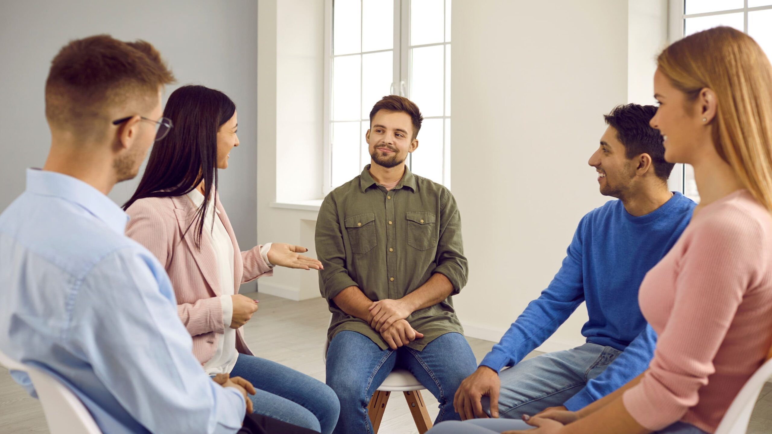 A group of people engaging in conversation during a 12-step program meeting.