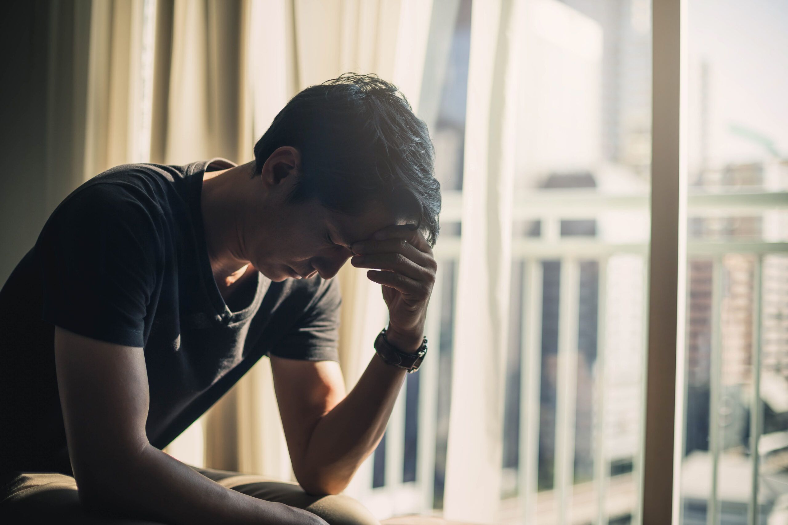 Sad man sitting on bed struggling with alcohol addiction