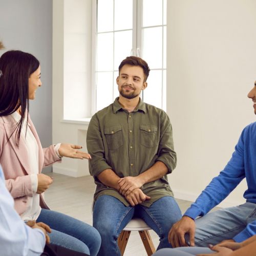 A group of people engaging in conversation during a 12-step program meeting.